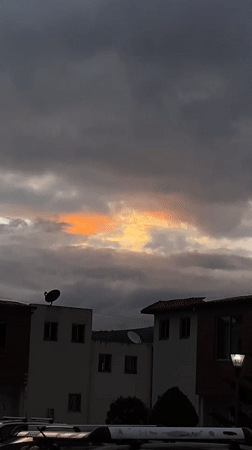 Orange light breaks through cloudy evening sky in Quito