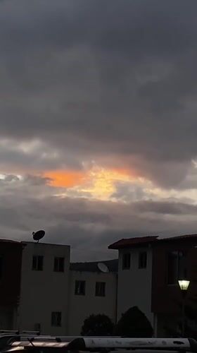 Orange light breaks through cloudy evening sky in Quito