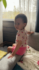 Child in pink outfit observed sitting on sofa in Wisła