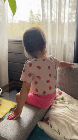 Child in pink outfit observed sitting on sofa in Wisła