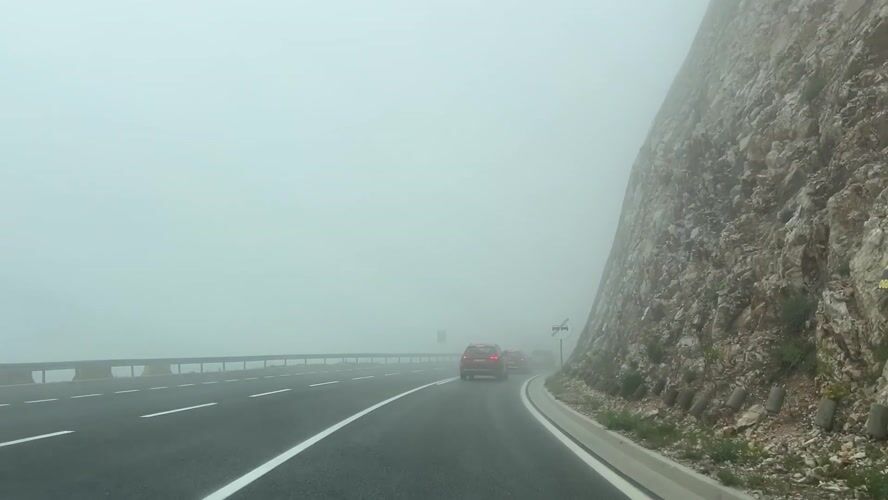 Driver navigates foggy mountain road in Montenegro