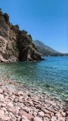 Tourists document scenic Adriatic coastline at Rafailovići beach cove