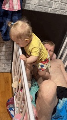 Father and toddler play together inside crib in Russia