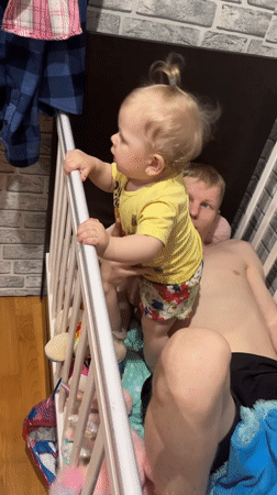 Father and toddler play together inside crib in Russia