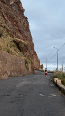 Hiker walks cracked coastal road near cliffs in Portugal