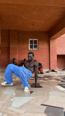 Young man breakdances for friends in covered Nigerian courtyard