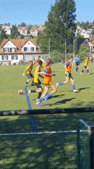 Soccer match played on sunny day with residential backdrop