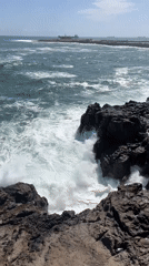 Waves crash against rocky Arica coastline under clear skies