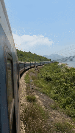 Train passenger records coastal landscape during early morning journey