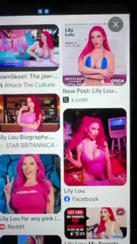 The video shows a smartphone screen displaying a Google image search for "Lily Lou". The search results show various images of a woman with bright pink hair, often wearing revealing clothing. A finger is seen tapping the screen, presumably navigating through the search results. The overall environment is a digital space within the smartphone, focused on the visual presentation of the search results.