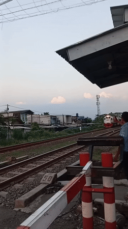 Passenger train crosses busy railway intersection in Semarang