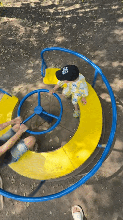 Children play on merry-go-round in Rusanovo park