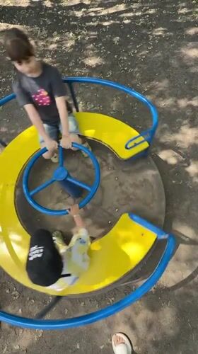 Children play on merry-go-round in Rusanovo park