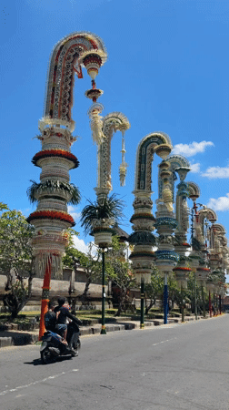 Traditional penjor bamboo decorations line Mengwi street in Bali