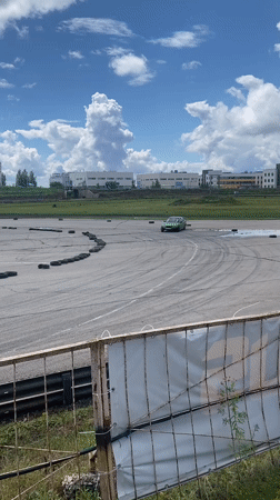Green car drifting through a smoky run on a Russian track
