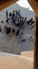 Children queue with containers for aid distribution in damaged urban area