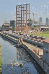 Mumbai residents navigate polluted urban landscape near industrial infrastructure