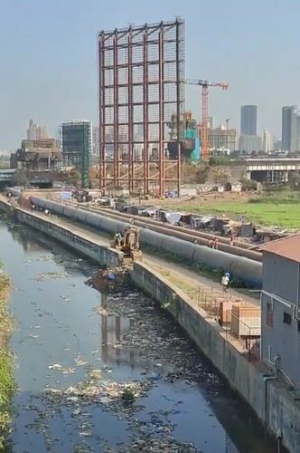 Mumbai residents navigate polluted urban landscape near industrial infrastructure