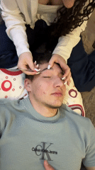 Woman grooms man's eyebrows indoors in Zlatograd, Bulgaria