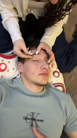 Woman grooms man's eyebrows indoors in Zlatograd, Bulgaria