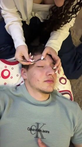 Woman grooms man's eyebrows indoors in Zlatograd, Bulgaria