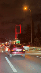 Night drive across a lit suspension bridge in heavy traffic