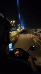 Nighttime motorcycle ride across bridge in Hong Gai Ward