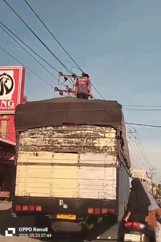 Man stands atop truck as woman follows on scooter