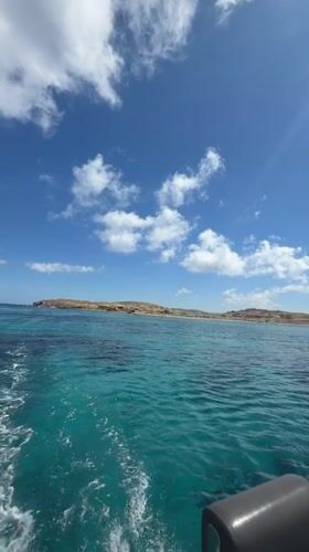 Boat approaches Delos island under sunny Mediterranean skies
