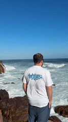 Man observes choppy ocean from rocky Cape Town coastline
