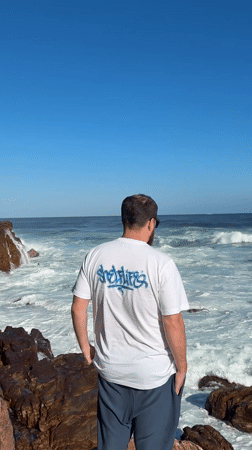 Man observes choppy ocean from rocky Cape Town coastline