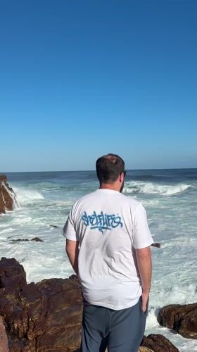 Man observes choppy ocean from rocky Cape Town coastline
