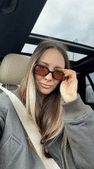 Woman puts on sunglasses while sitting in car in Moscow