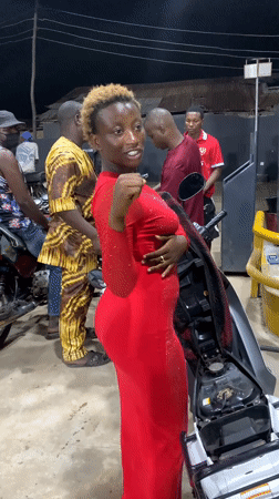 Woman in red dress rides motorcycle at Lokoja gas station