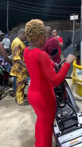 Woman in red dress rides motorcycle at Lokoja gas station
