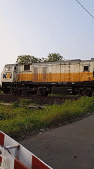 KAI freight train crosses rural railroad intersection in Sidorejo