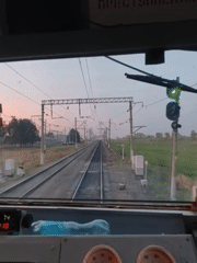 Train cabin POV footage shows forward movement past trackside signals