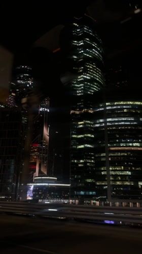 Moscow skyscrapers illuminated at night captured from moving vehicle