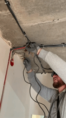 Worker performs electrical maintenance on concrete ceiling in Saint Petersburg