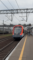 Moscow commuter train arrives at station amid city skyline