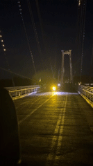 Nighttime pedestrian activity captured around illuminated suspension bridge