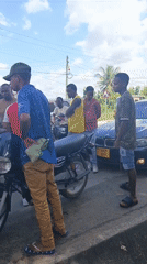 Crowd gathers around black BMW on Dar es Salaam street
