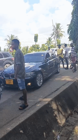 Crowd gathers around black BMW on Dar es Salaam street