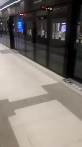 The video shows a walkway and the closed doors of a Bank Al-Bilad branch. The floor is tiled in a pale color and has a textured strip. The bank's glass doors have chevron pattern decals. Inside the bank, displays of jewelry and other items are visible.