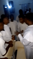 Men in white gather for funeral service with singing