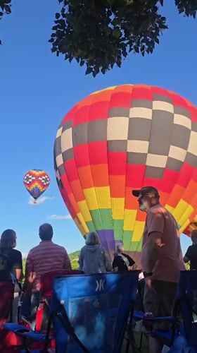 Colorful hot air balloons lift off at an outdoor gathering