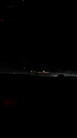 The video shows a first-person view from inside a car driving on a highway at night. Headlights from other vehicles are visible in the distance. The car's dashboard is faintly illuminated. A music player on the dashboard displays an image.  The overall environment is dark.