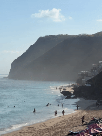 Crowded Kuta Selatan beach below dramatic cliffs, Bali