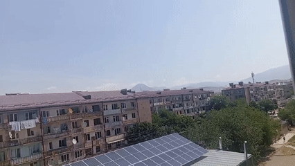 Apartment building with solar panels observed under clear morning sky