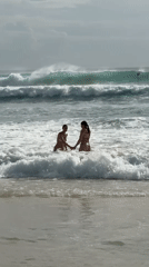 Two women share moment in ocean waves, Kuta Selatan